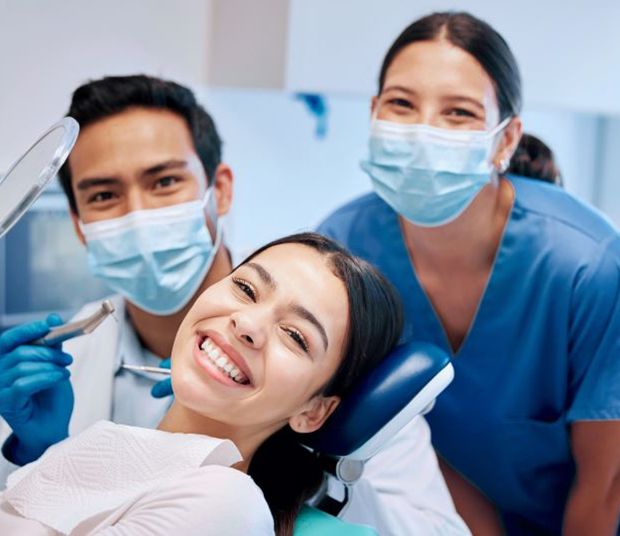 Happy dental patient posing with dental team